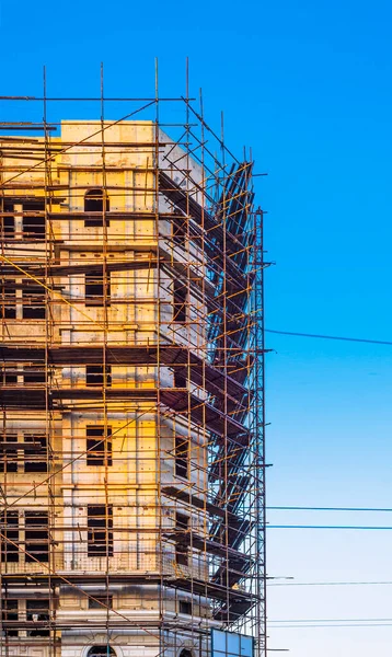 site scaffolding Apartment building under construction on a sunny day Multi-storey residential wooden structure street tlong exposure. car