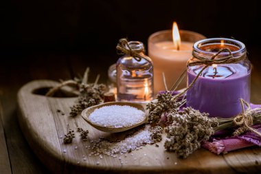 Glass bottle Lavender essential oil dried seed  aromatherapy spa massage concept. herb Purple candle wood table background sea salt still life rustic cutting board napkin.