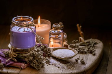 Glass bottle Lavender essential oil dried seed  aromatherapy spa massage concept. herb Purple candle wood table background sea salt still life rustic cutting board napkin.