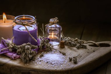 Glass bottle Lavender essential oil dried seed  aromatherapy spa massage concept. herb Purple candle wood table background sea salt still life rustic cutting board napkin.