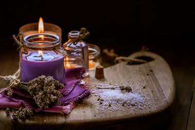 Glass bottle Lavender essential oil dried seed  aromatherapy spa massage concept. herb Purple candle wood table background sea salt still life rustic cutting board napkin.