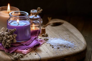 Glass bottle Lavender essential oil dried seed  aromatherapy spa massage concept. herb Purple candle wood table background sea salt still life rustic cutting board napkin.