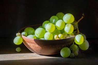 Organik çekirdeksiz yeşil üzüm, kireç, seramik çanak çanak, ahşap masa.