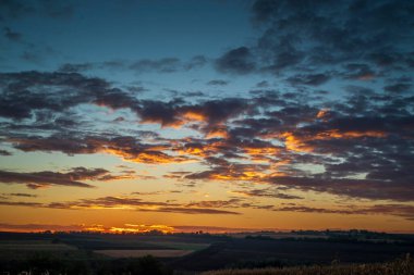Akşamları gökyüzü vanilyalı. Ufukta altın pembe sirrus bulutları olan gök mavisi günbatımı cenneti. Pastel renkli gökyüzünün panoramik görüntüsü. Doğada güzellik.
