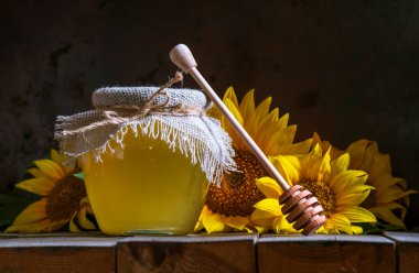 Şeffaf bir kavanozda şeffaf ayçiçeği balı, çuval peçete kapağı kapağı, sağlıklı beslenme konsepti, eski ahşap arka plan çömleği, hala koyu yiyecek cam kasesi.