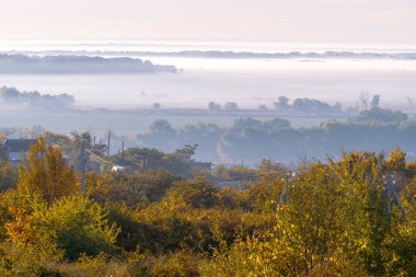 Sonbaharda yamaçta gizemli bir sis, ağaçlar ıslak, nemli orman sisi güzel Olanesti Moldova Panoramik manzara kırsal köy erken sabah nehir dinamosu