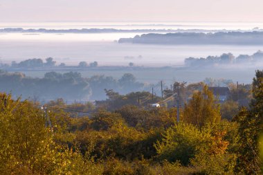 Sonbaharda yamaçta gizemli bir sis, ağaçlar ıslak, nemli orman sisi güzel Olanesti Moldova Panoramik manzara kırsal köy erken sabah nehir dinamosu
