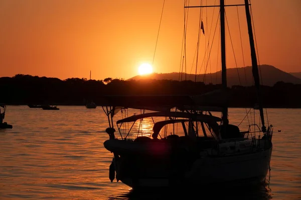 Белый парусник плывет по морю с оранжевым закатом — стоковое фото