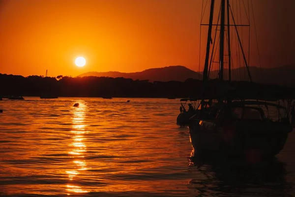 A white sailboat sails on the sea with an orange sunset Royalty Free Stock Photos