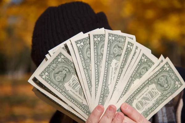  Önünde Amerikan doları tutan siyah şapkalı bir adam.