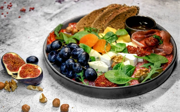 Dilimlenmiş peynirli şarap tabağı, et ve soslu meyve.