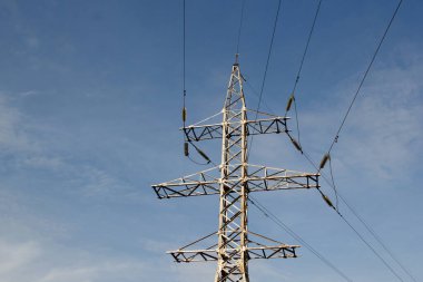 Mavi gökyüzünün arka planında yüksek voltajlı elektrik hatları. 