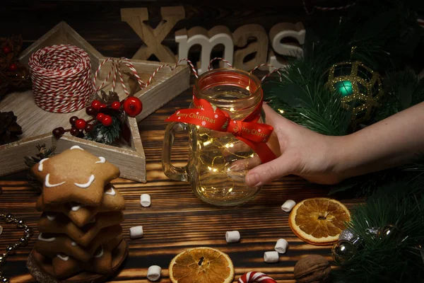 Görünmez bir çocuğun eli ahşap bir masada Noel kompozisyonu yapıyor.