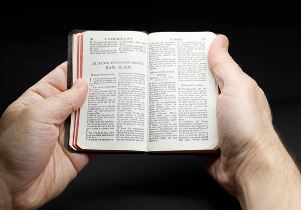 male hands holding open pocket bible in Spanish