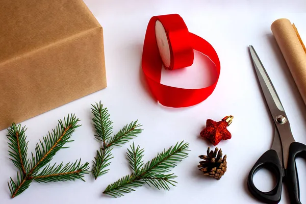 Stap voor stap. Stap twee. Wikkel een kerstcadeau in ambachtelijk papier en versier het met dennentakken en kerstspeelgoed. Instructies voor cadeauverpakkingen. — Stockfoto