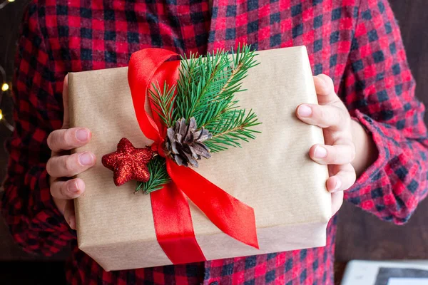 Het kind houdt het gekoesterde kerstgeschenk in zijn handen. Het meisje geeft het cadeau.. — Stockfoto