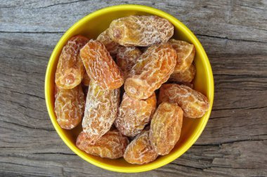 Eski ahşap arka plandaki bir kasede kuru tarihler. 