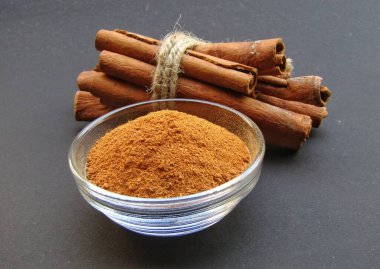 Siyah arka planda bir kasede tarçın tozu 