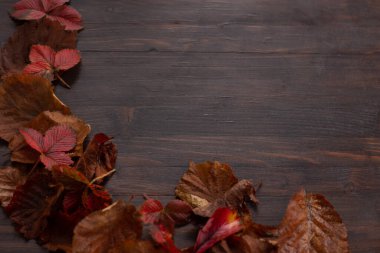 Red, brown old autumn leaves on wooden table background