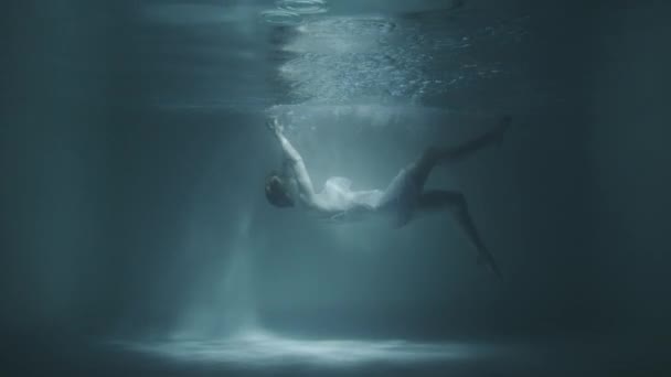Una chica en un vestido blanco cae bajo el agua — Vídeo de stock