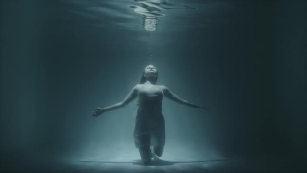 Het meisje bevroor onder water onder de bodem omhoog kijkend — Stockvideo