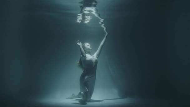 Het meisje bevroor onder water onder de bodem omhoog kijkend — Stockvideo