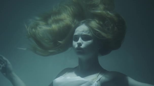 Close-up of a beautiful girl with red hair in a white dress froze under water — Stock Video