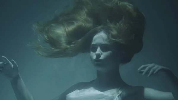 Primer plano de una hermosa chica con el pelo rojo en un vestido blanco se congeló bajo el agua —  Fotos de Stock