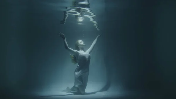 Chica congelado bajo el agua en la parte inferior mirando hacia arriba — Foto de Stock