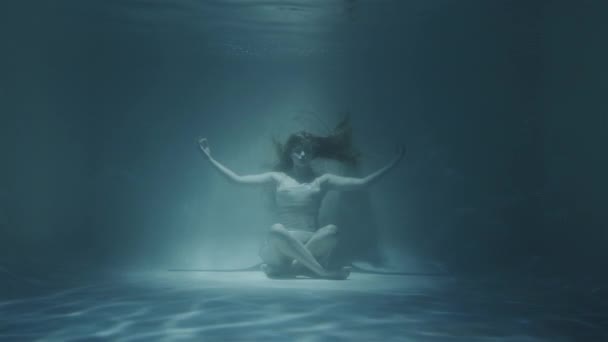 Rudovlasá žena meditující pod vodou v bílých šatech — Stock video