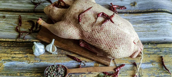 Raw duck with spices is ready to cook. Fresh duck meat on a wooden food tray. Whole duck close-up.