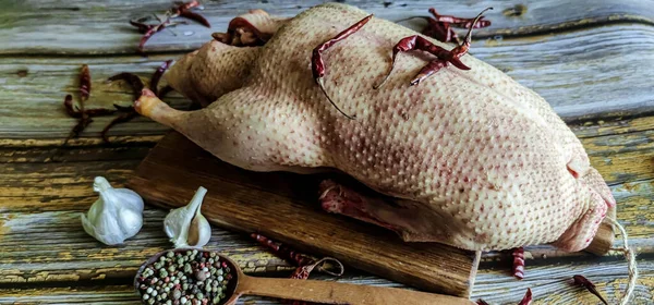 Raw duck with spices is ready to cook. Fresh duck meat on a wooden food tray. Whole duck close-up.