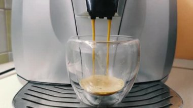Kahve makinesinin fincanındaki görüntüler. Ev yapımı sıcak Espresso. Taze kahve akıyor. Sabahları kavrulmuş sade kahve içmek..