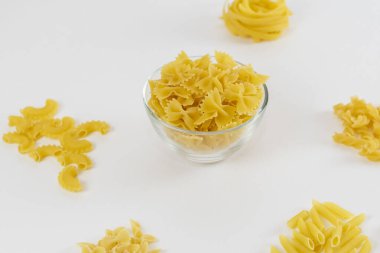 Çeşitli tipte makarnalar beyazların üzerine yayılır. Yemek pişirme konsepti. Çiğ makarna düzeni.