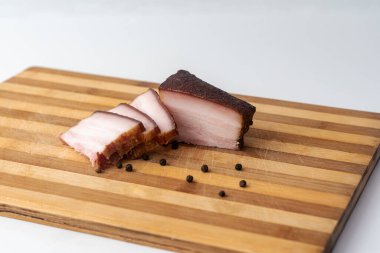Tütsülenmiş domuz yağı, domuz pastırması, yarım dilim, ahşap bir arka planda. Domuz yağı. Korunmuş domuz eti.
