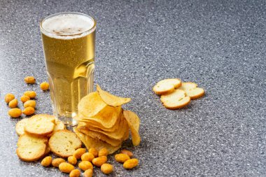 Bira ve patates cipsi. Bir bardak light bira. Cips, fındık, kraker koyu mermerde atıştırmak için birebirdir. Bira festivali, pab, restoran reklamı için iyi. Yiyecek ve içecek..