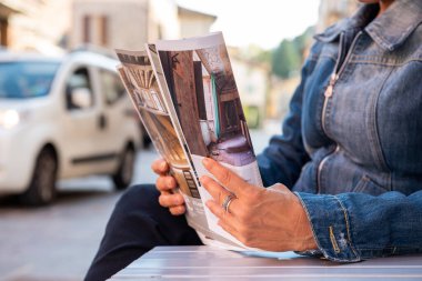 Modern kafede kitap okuyan bir kadının yakın plan görüntüsü.