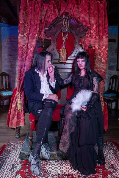 中世の雰囲気の中で玉座に座るゴシック服の男と女 吸血鬼 — ストック写真