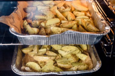 Fırında patatesler pişiyor, baharatlı ve baharatlı. Alüminyum tepsilerde.