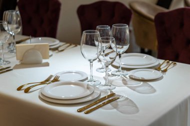 Chic and elegant, gold-plated cutlery and white plates, table setting with empty plates.