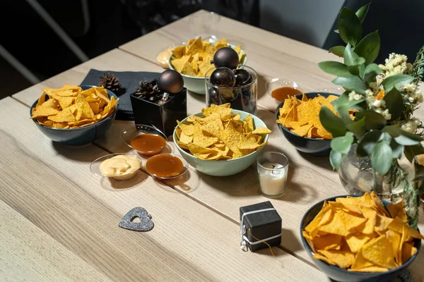 En tallrik med läckra vanligt nacho tortilla majschips på ett vackert bord. Jultema, bollar och dekorationer. — Stockfoto
