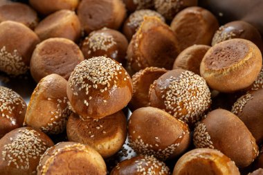 The homemade bread rolls with sesame. Lots of rolls are poured onto the baking sheet.