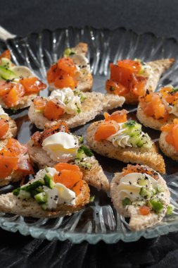 Salmon sandwiches, cream cheese and cucumber on transparent plate. Healthy breakfast or healthy snack.