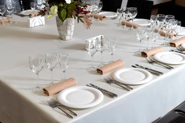Close up new white porcelain tableware plates on white tablecloths and empty wine glasses ready for dinner. — Stockfoto