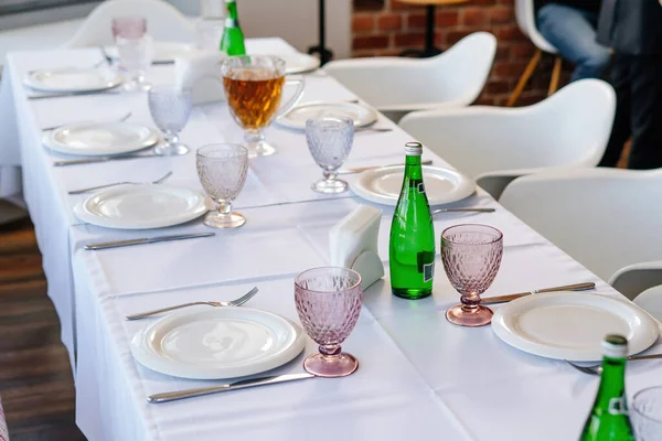 Table setting with white tablecloth, plates and cutlery laid out. — Stock Photo, Image