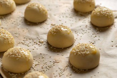 Hamburger çörekleri ve susam tohumları pişirmek için hazırlandı. Pişirme kağıdının üzerine yerleştirilmiş..