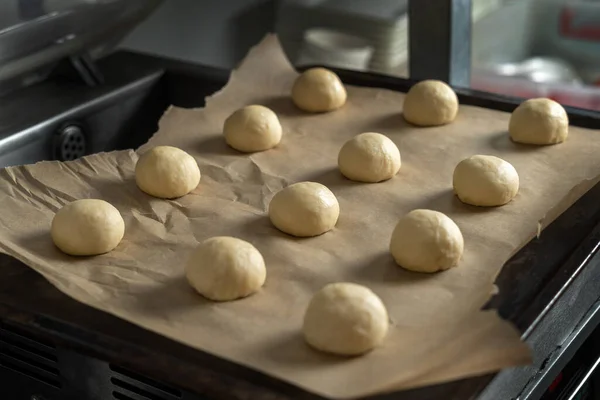 Bułki hamburgerowe z nasionami sezamu przygotowane do pieczenia. Arkusz do pieczenia ze ślepakami. — Zdjęcie stockowe