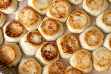 Pişirme tepsisinde cheesecake, yemek odasında aşçı. Güzel, pembe ve kızarmış.