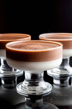 Siyah arka planda cam bardakta jöle. Vazolar siyah cam arka planda yansıtılır.