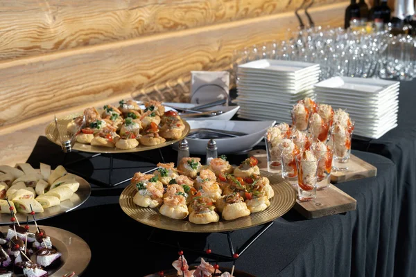 Um deleite para um buffet ou uma festa em casa. A mesa está reservada para o catering. Toalhas de mesa pretas, luz dura. — Fotografia de Stock